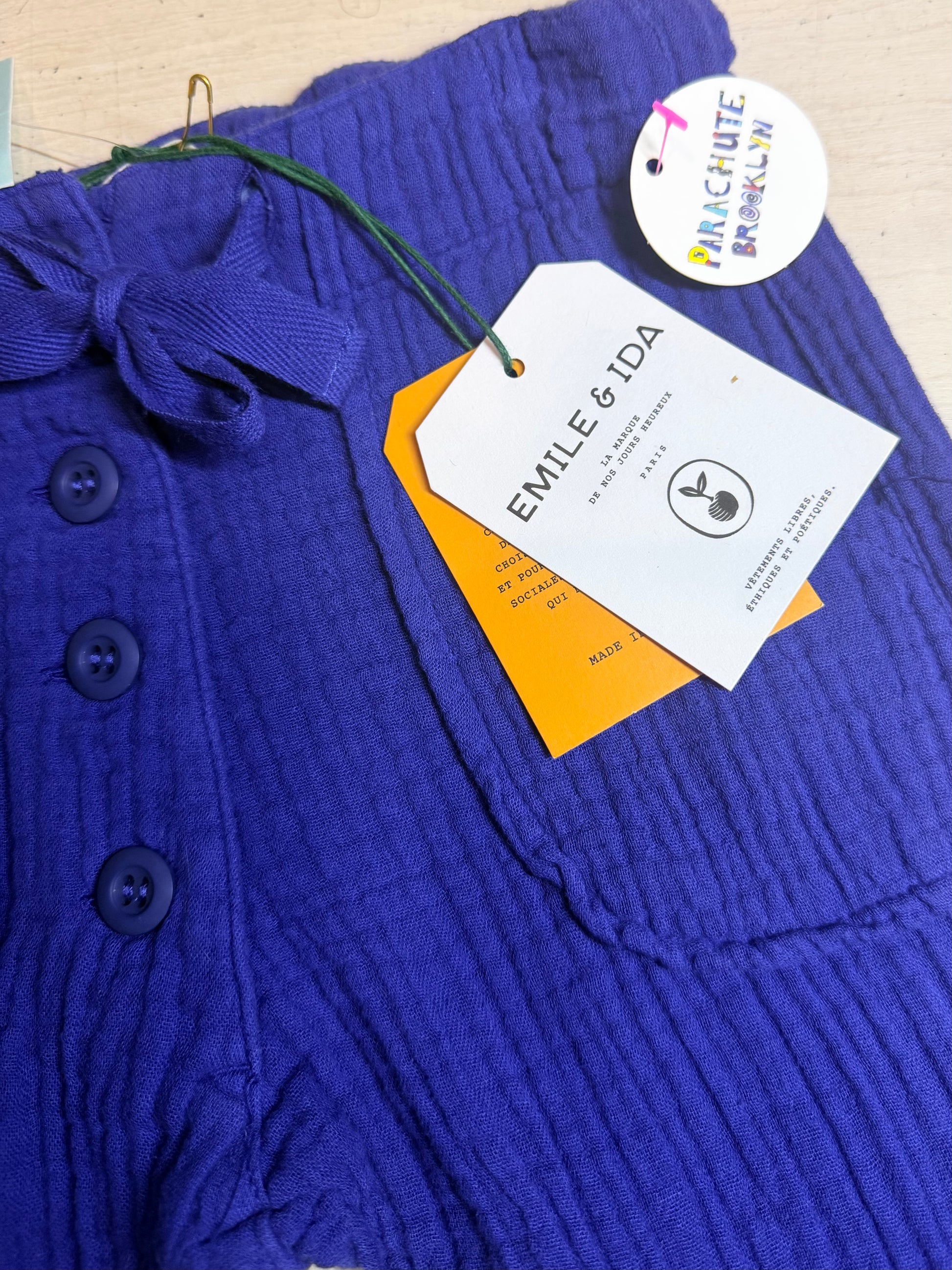 Blue textured garment with a brand tag on a beige background