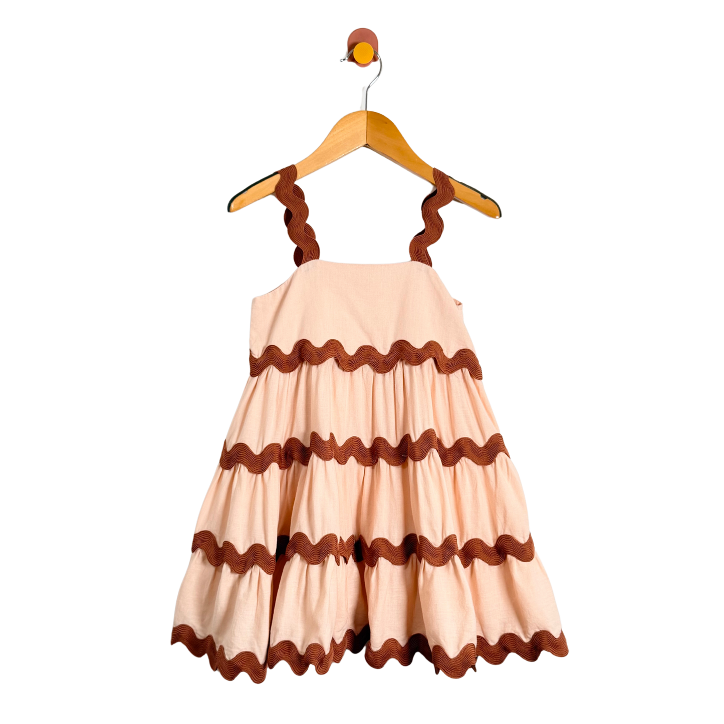 Beige dress with brown ruffled details on a hanger against a white background