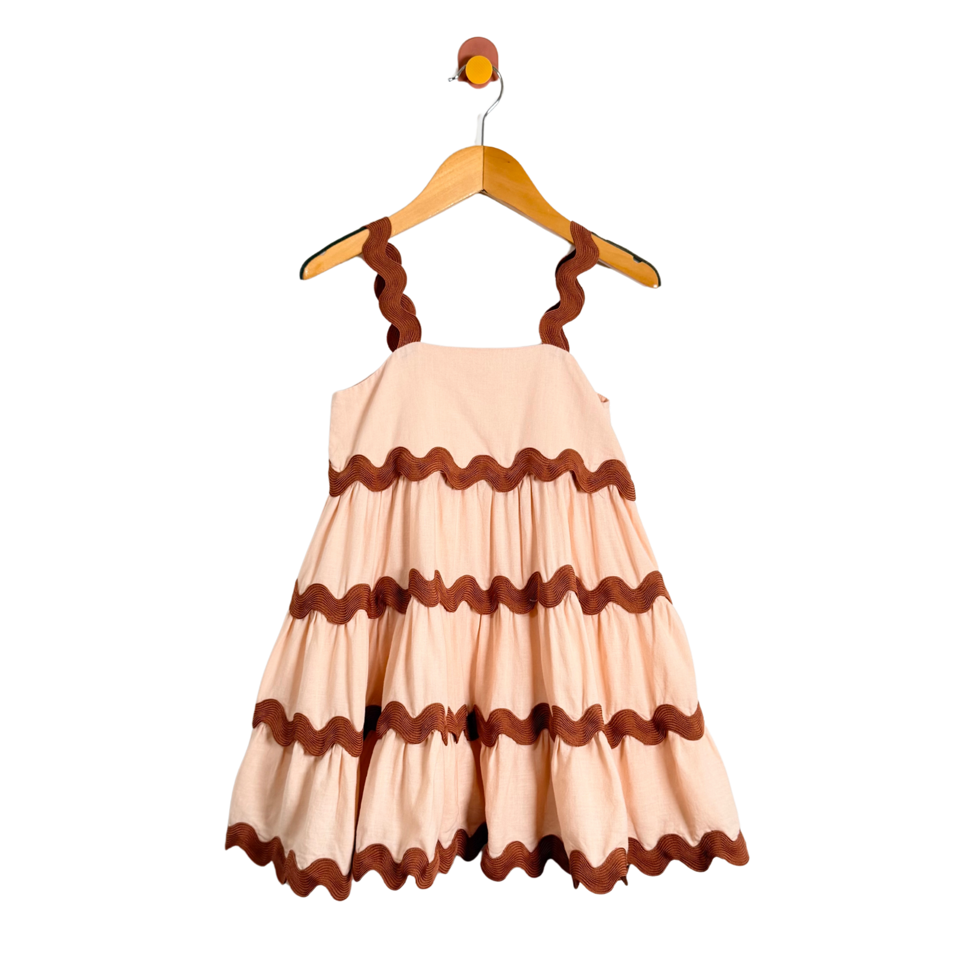 Beige dress with brown ruffled details on a hanger against a white background