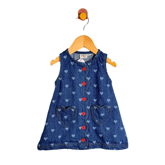 Blue denim dress with heart patterns on a wooden hanger against a white background