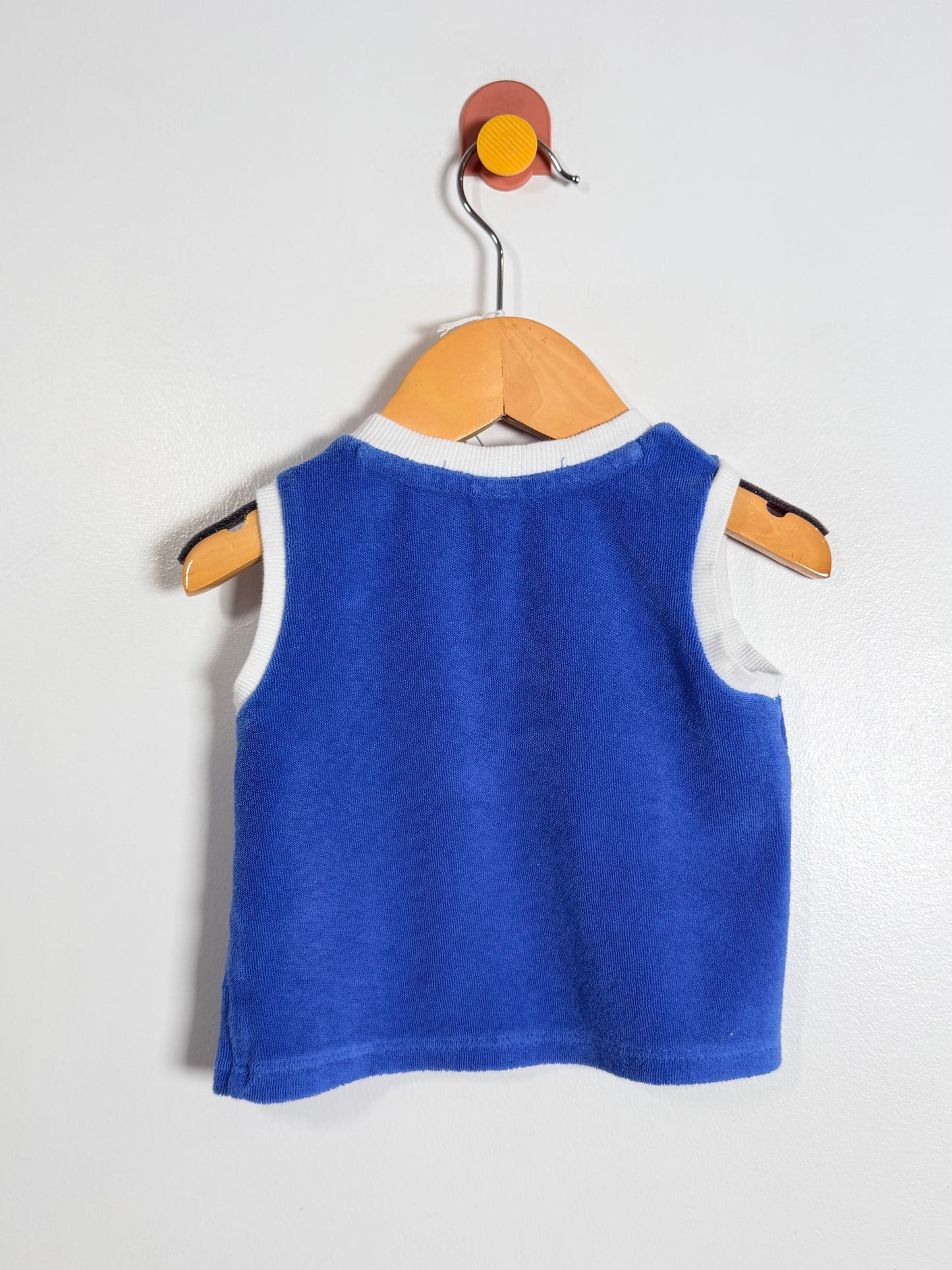 Blue sleeveless shirt on a wooden hanger against a white background
