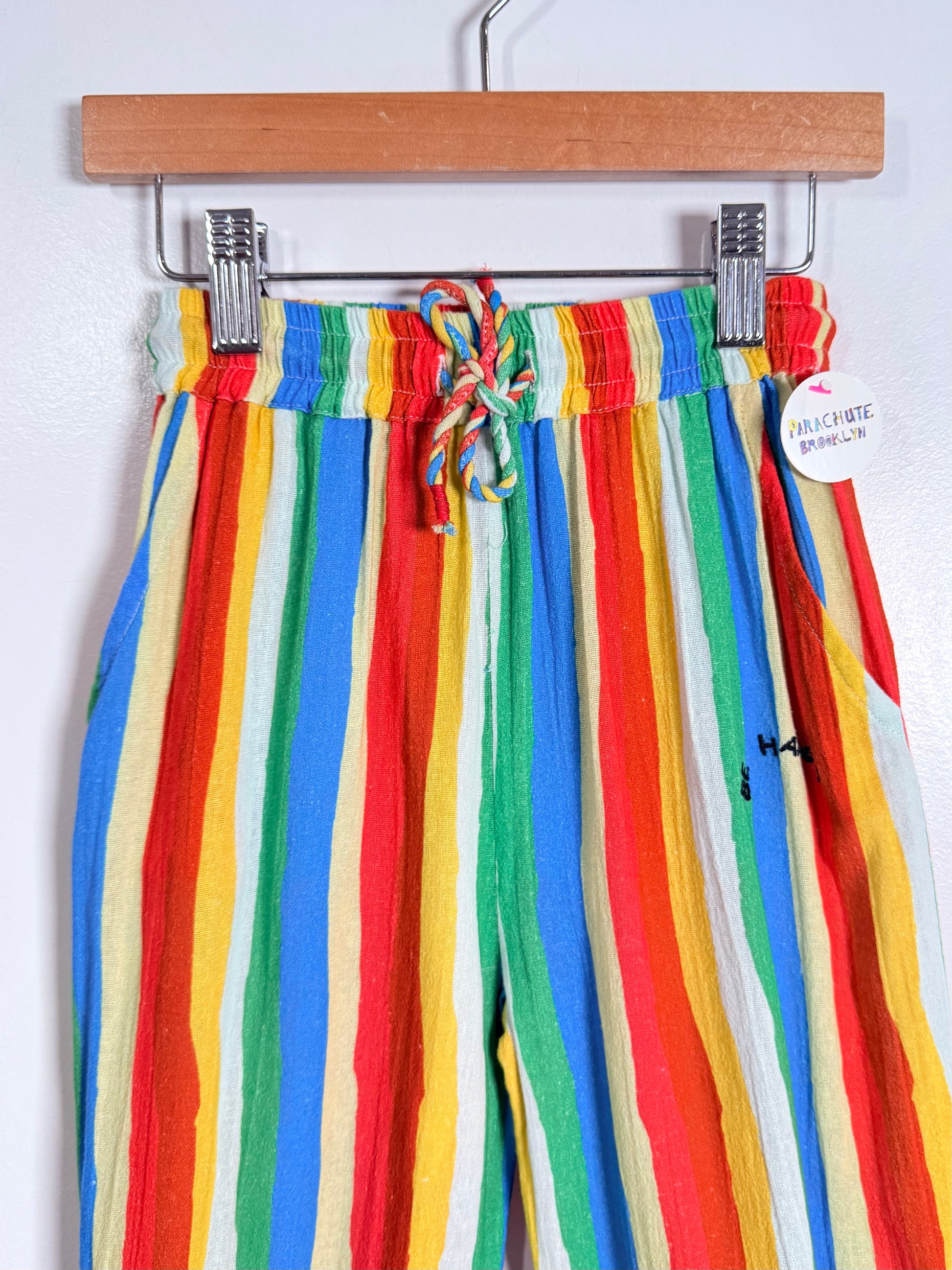 Colorful striped pants on a hanger against a white background