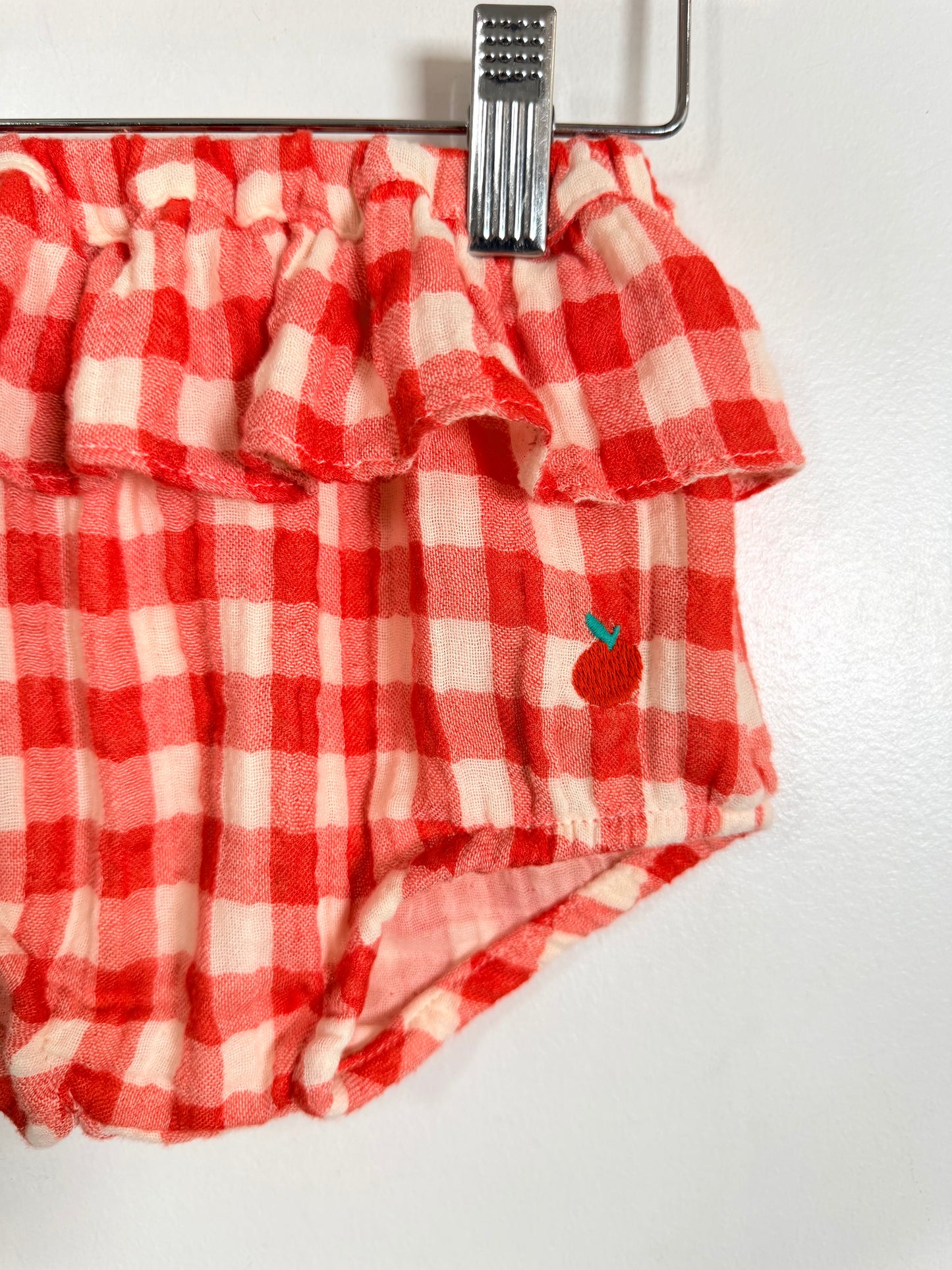 Red and white checkered fabric with a small apple design on a white background