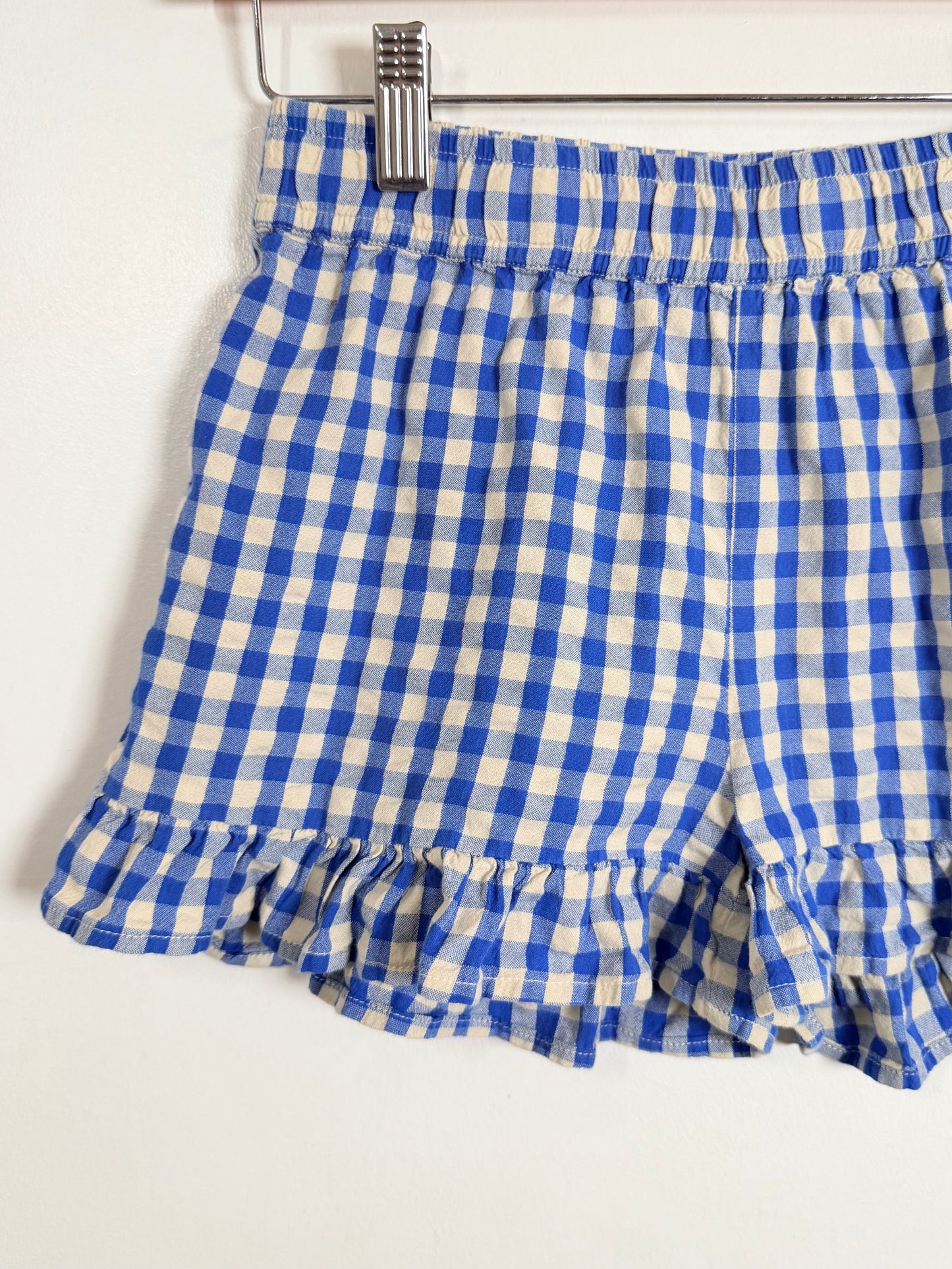 Blue and white checkered shorts on a hanger against a white background