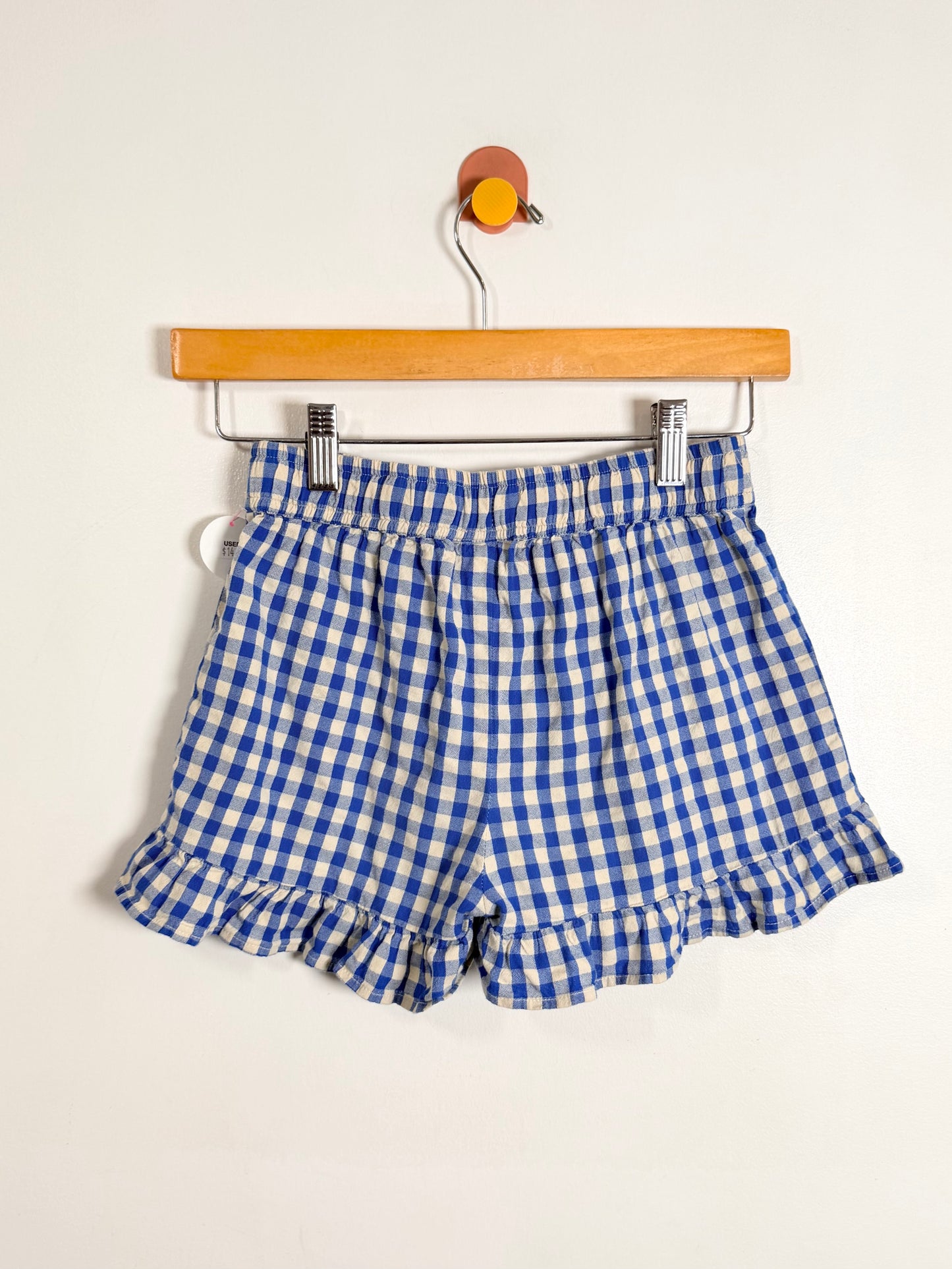 Blue and white checkered shorts on a hanger against a white background