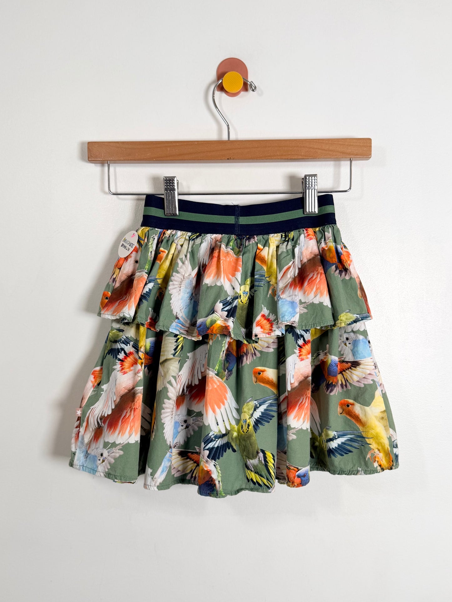 Skirt with bird print on a wooden hanger against a white background