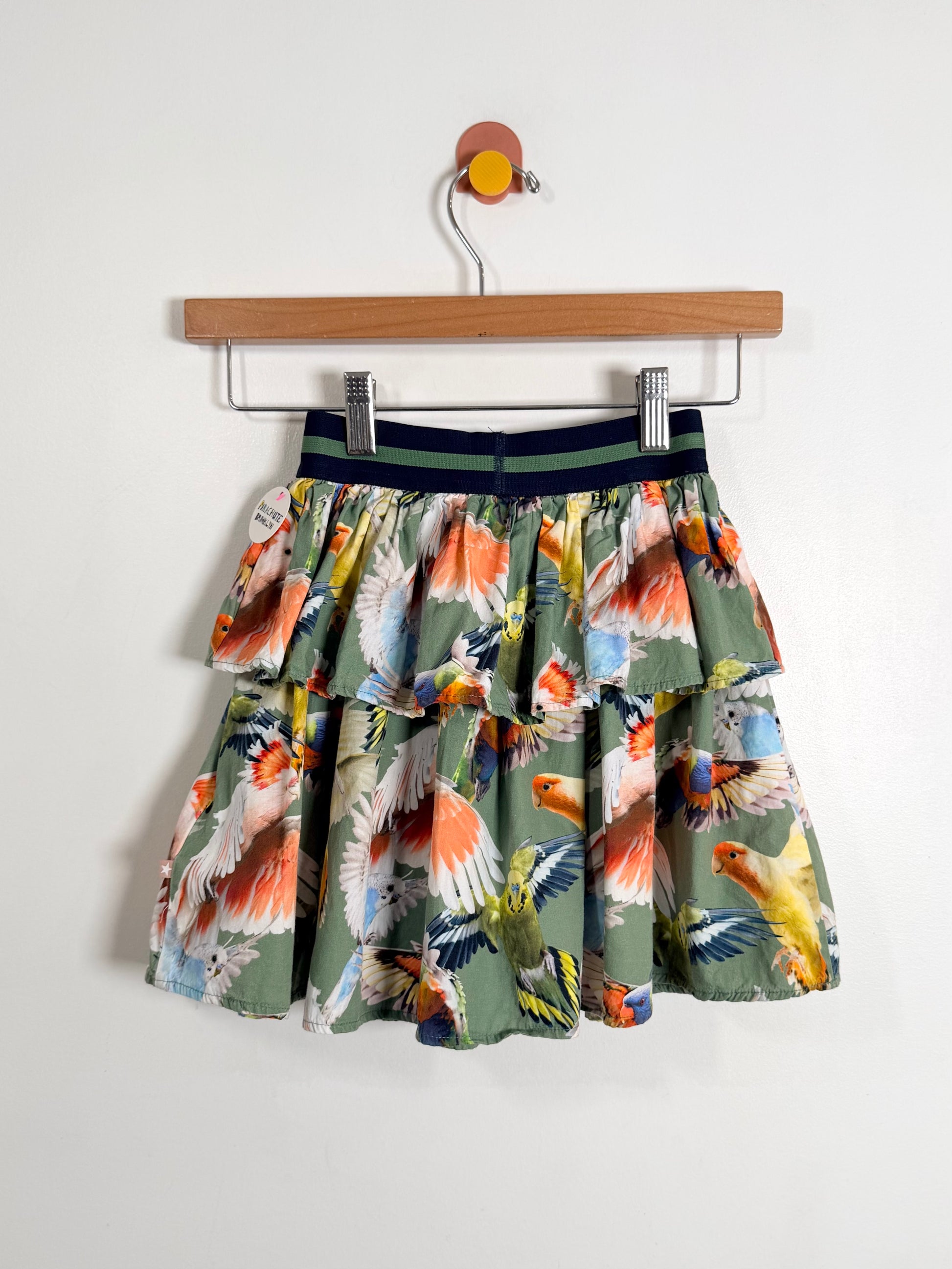 Skirt with bird print on a wooden hanger against a white background