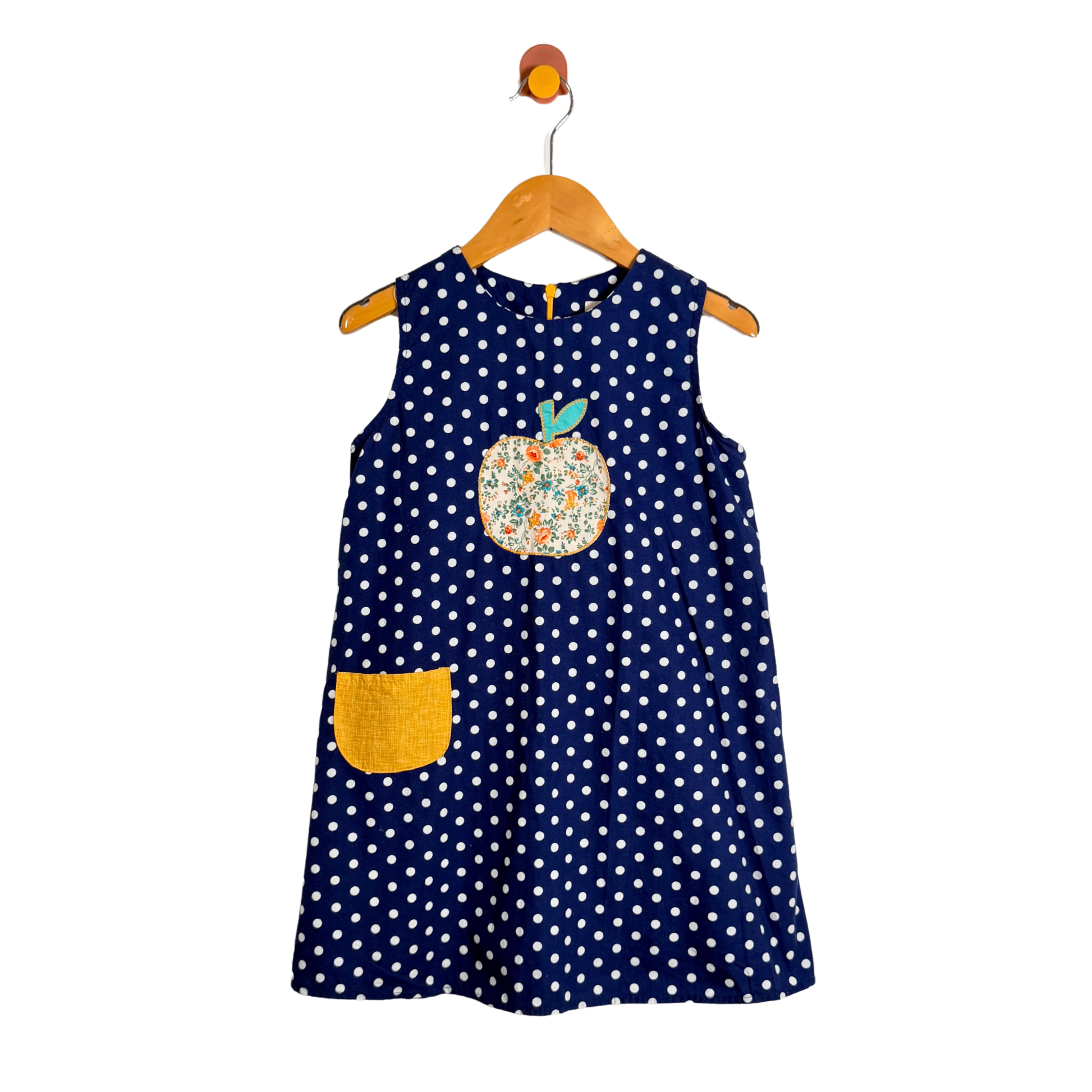Navy blue polka dot dress with a floral applique on a wooden hanger against a white background