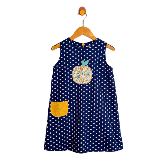 Navy blue polka dot dress with a floral applique on a wooden hanger against a white background