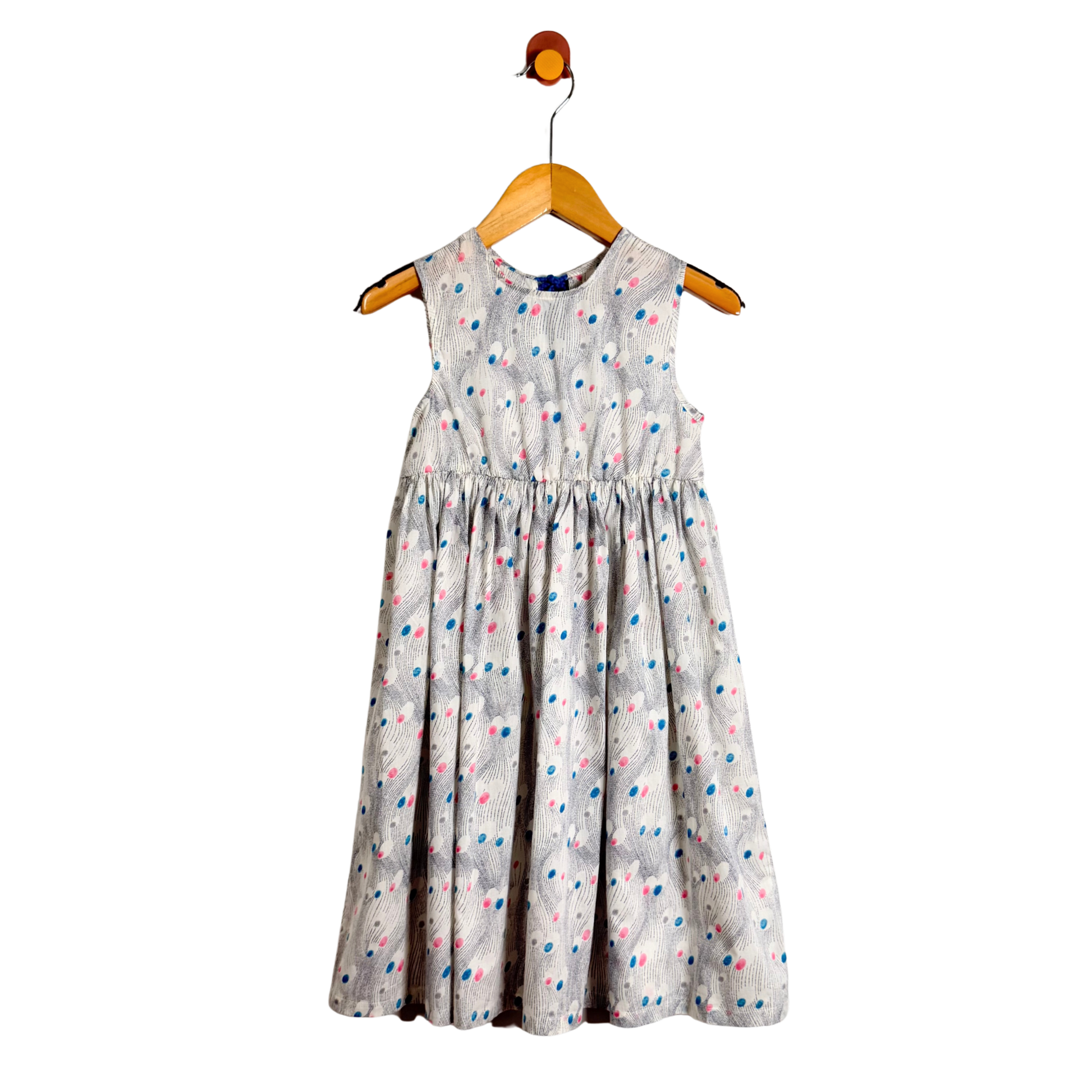 White dress with colorful polka dots on a wooden hanger against a white background