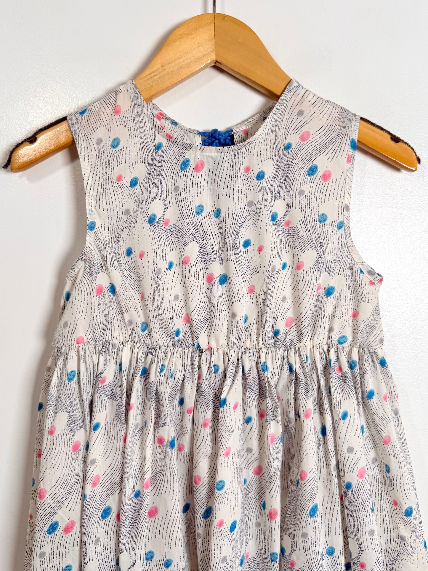Children's dress with a pattern on a wooden hanger against a white background