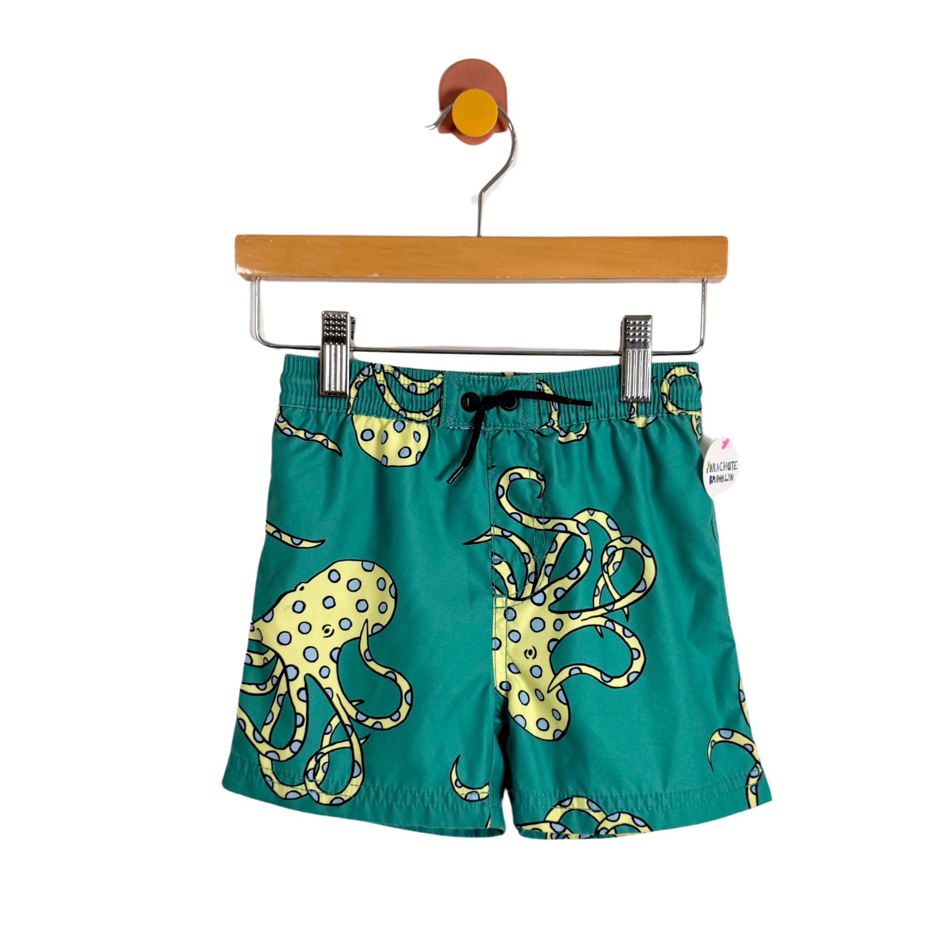 Green shorts with octopus design on a hanger against a white background
