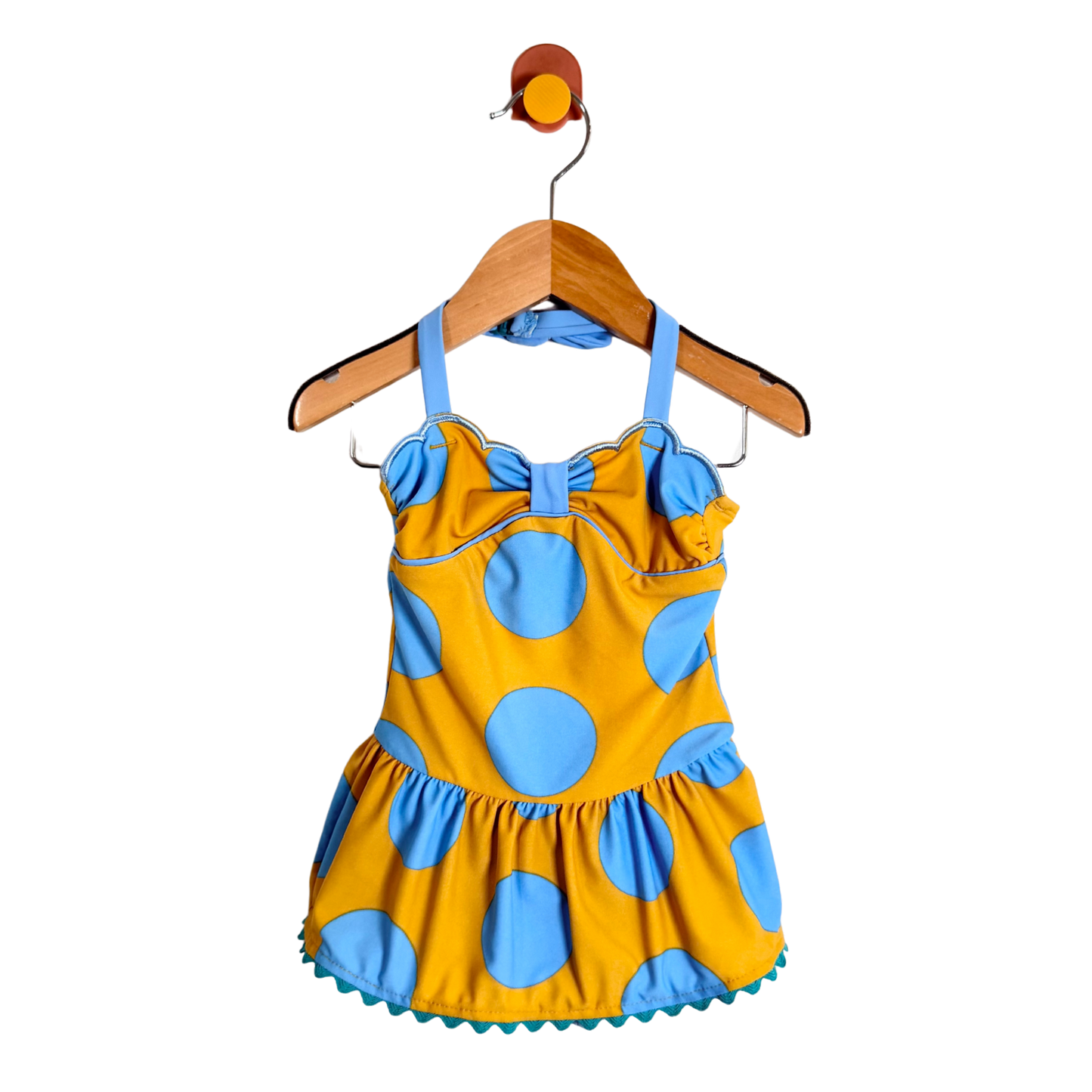 Yellow and blue polka dot dress on a wooden hanger against a white background