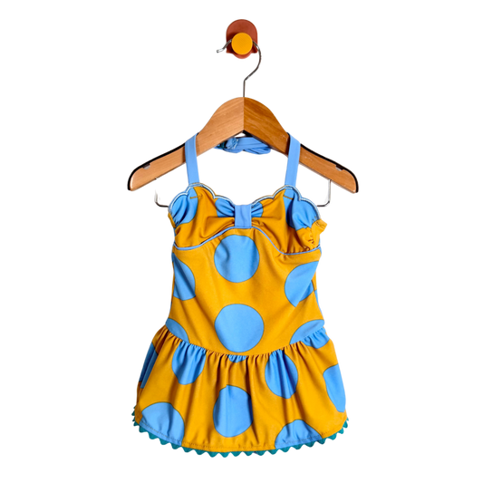 Yellow and blue polka dot dress on a wooden hanger against a white background