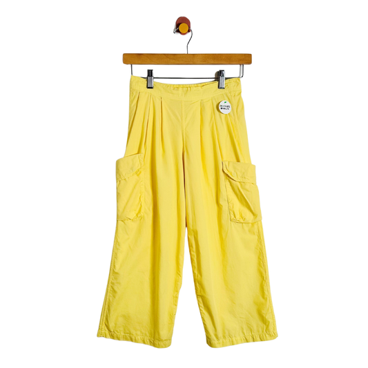 Bright yellow wide-leg cargo pants with side flap pockets, hanging from a wooden hanger against a plain white background.