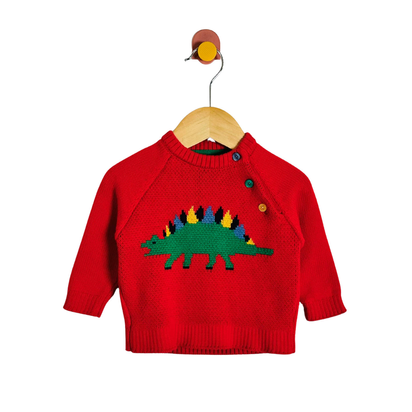A red knit baby sweater with a colorful knitted dinosaur design on the chest, hanging on a wooden hanger against a plain white background.