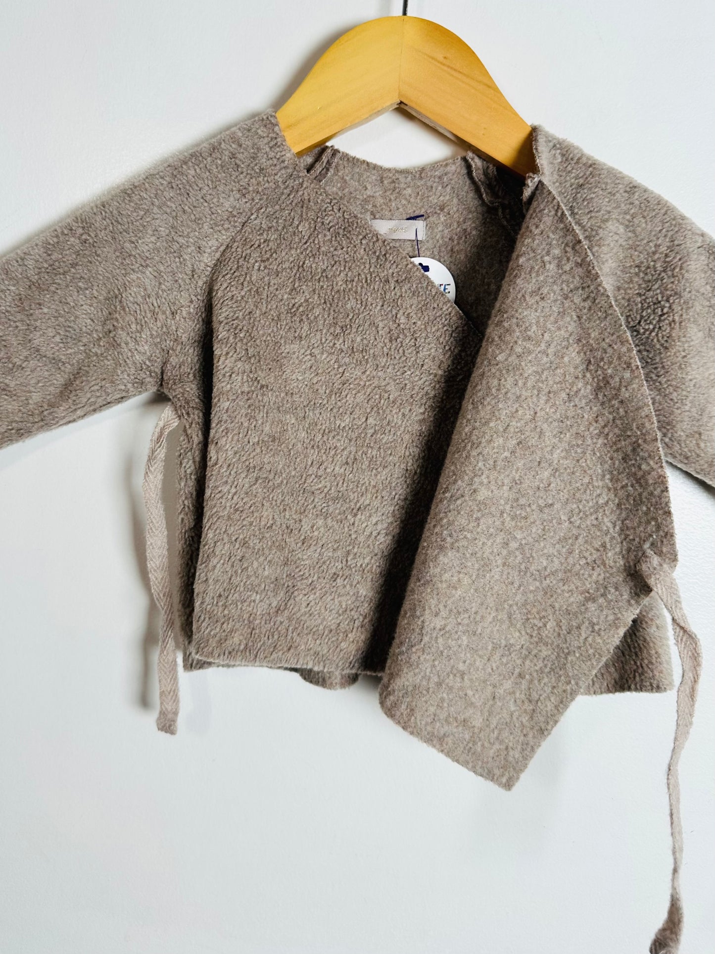 Brown cardigan on a hanger against a white background