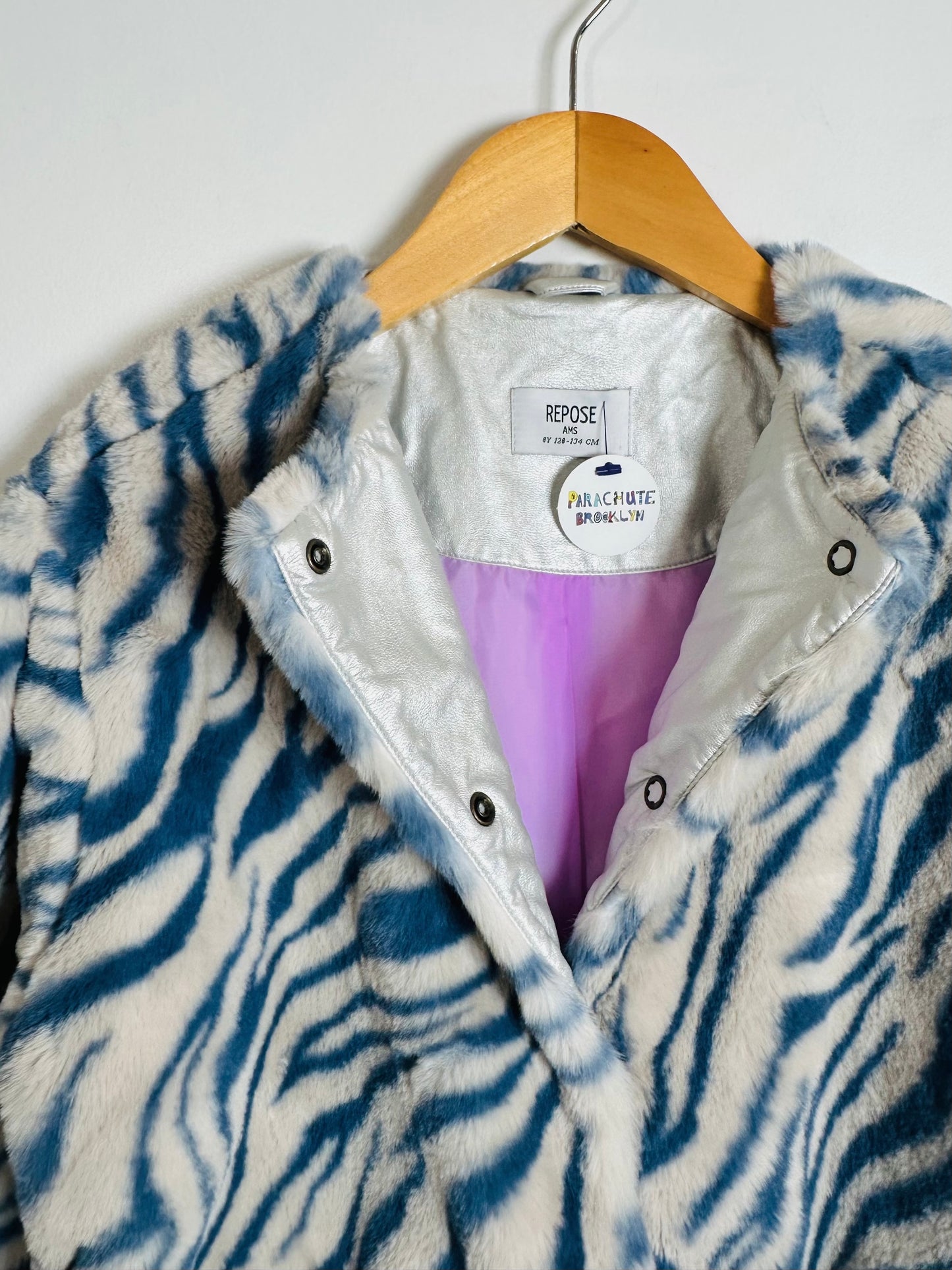 Zebra-patterned jacket with a visible brand label on a wooden hanger against a white background