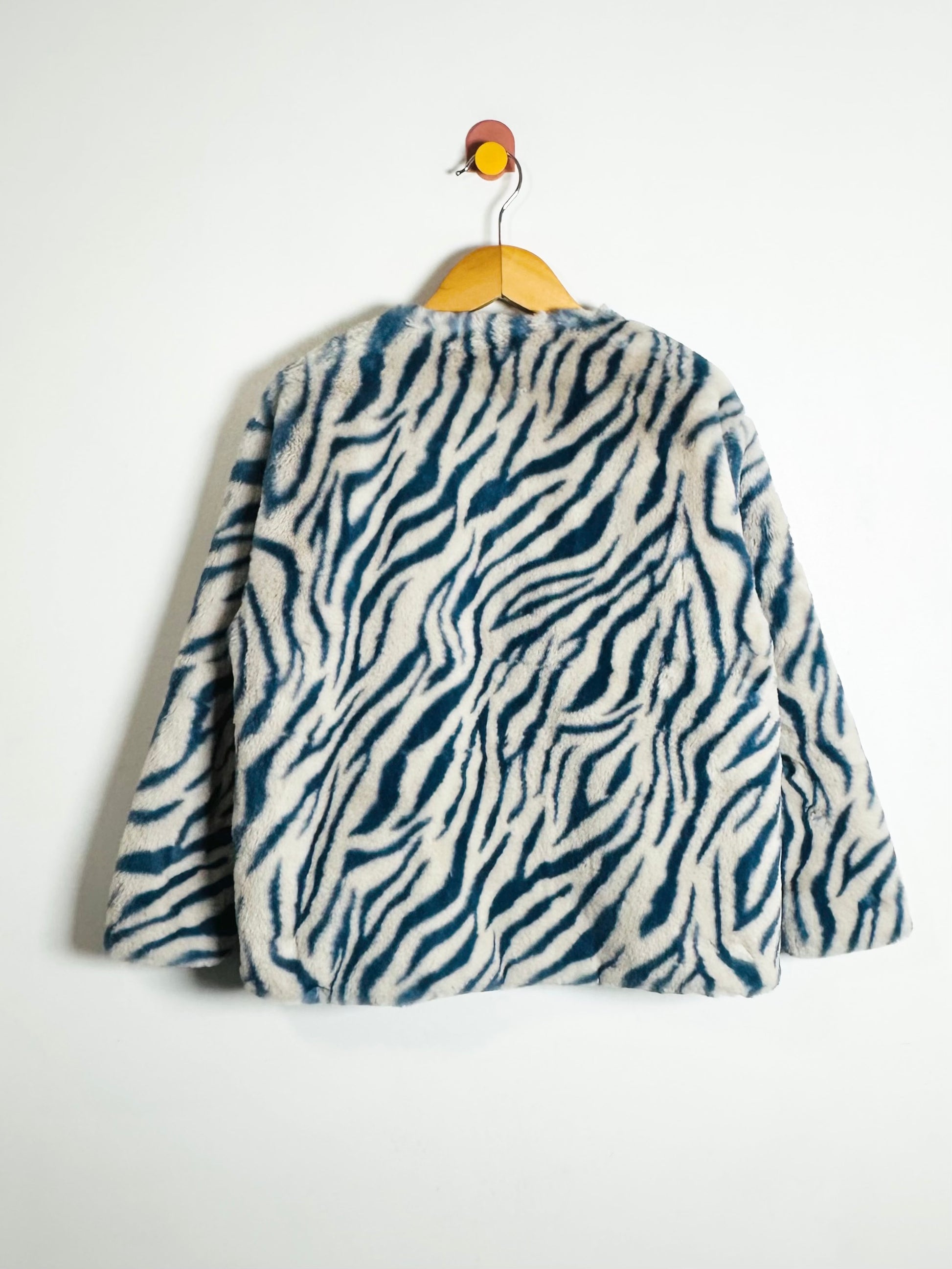 Zebra-patterned jacket on a hanger against a white background