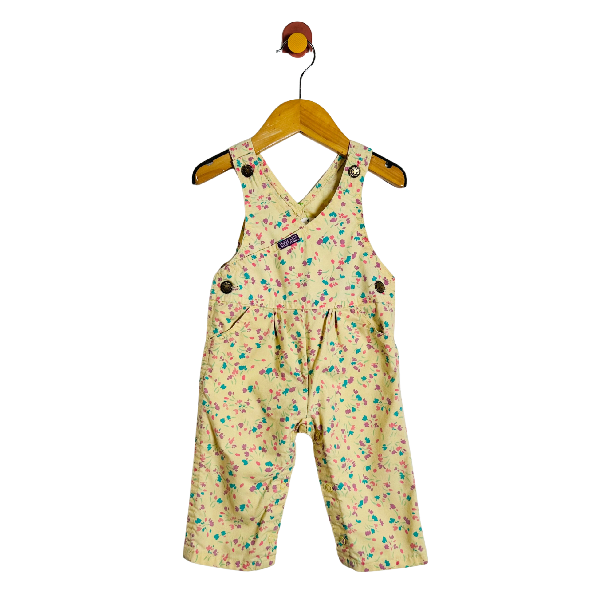 A baby romper in a yellow color with a colorful floral print, hanging on a wooden hanger against a plain white background.