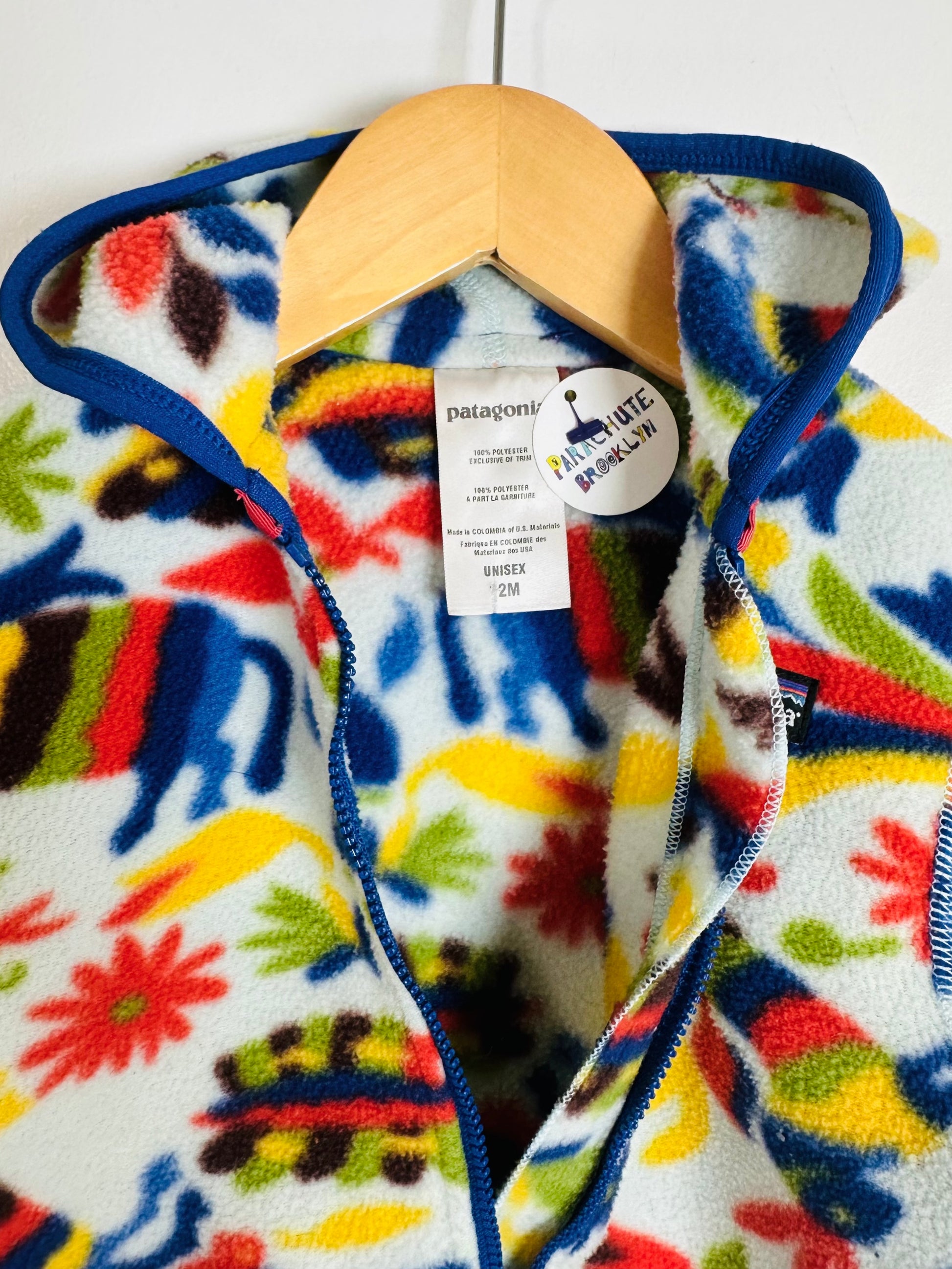 Colorful fleece jacket with a pattern on a hanger against a white background