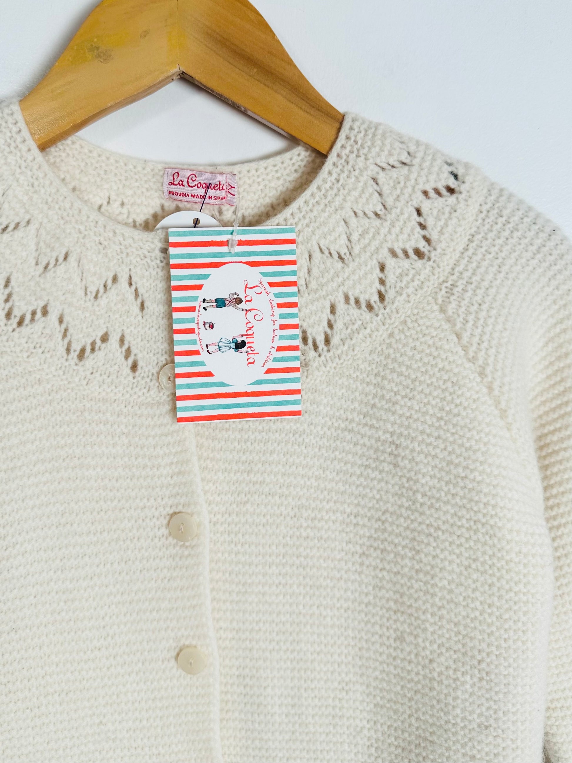 Knitted cardigan with a brand tag on a wooden hanger