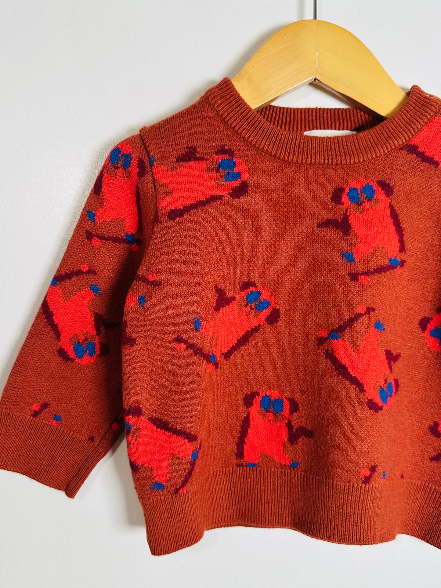Brown sweater with red dog pattern on a hanger against a white background