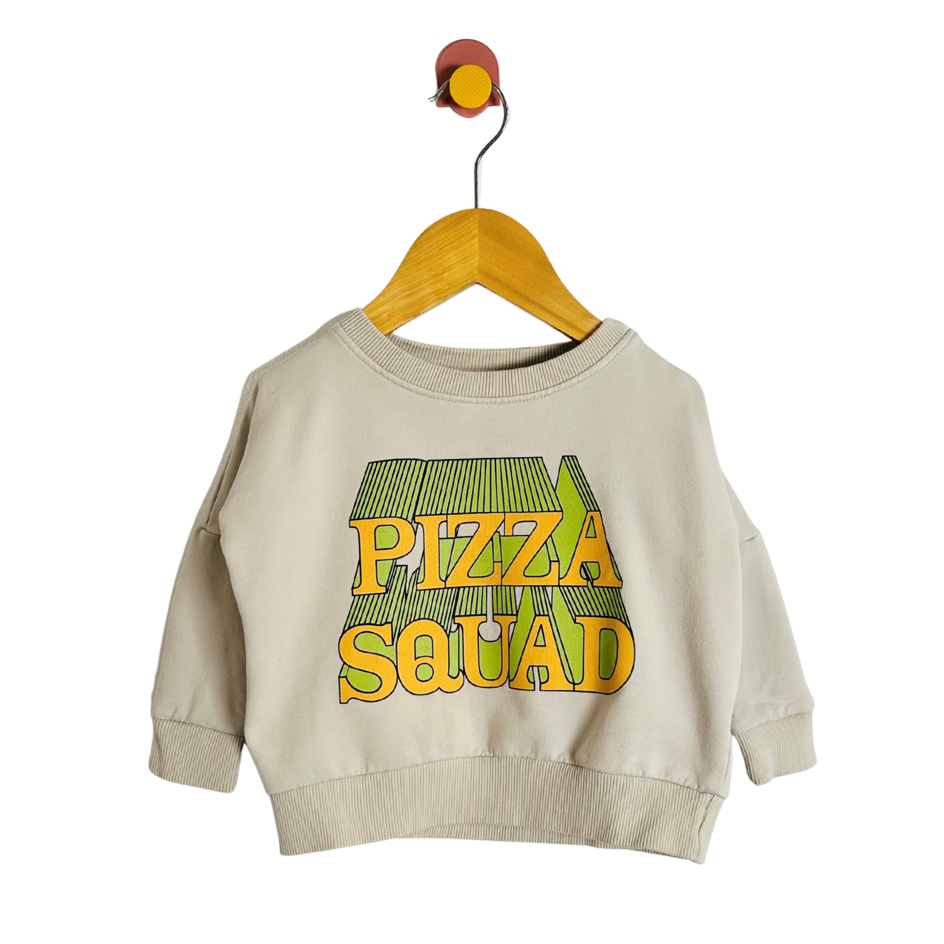 Beige sweatshirt with 'Pizza Squad' text on a hanger against a white background