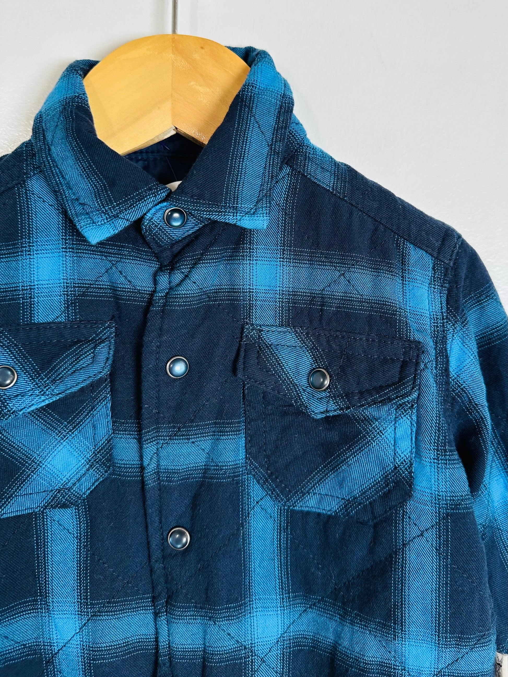 Blue plaid jacket on a hanger against a white background