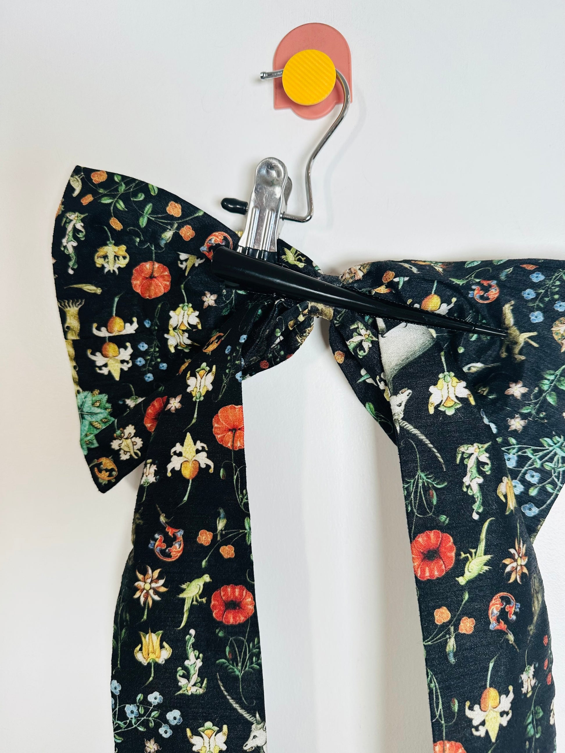 Floral-patterned bow tie on a hanger against a white background