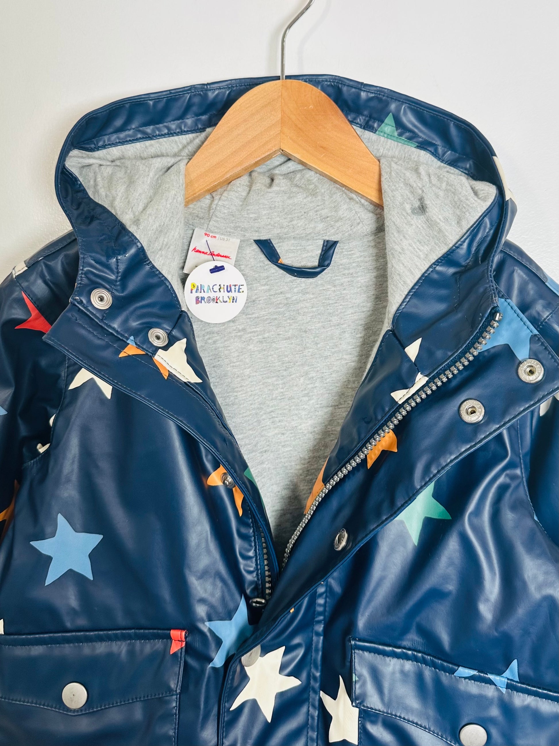 Children's blue raincoat with star patterns on a hanger against a white background