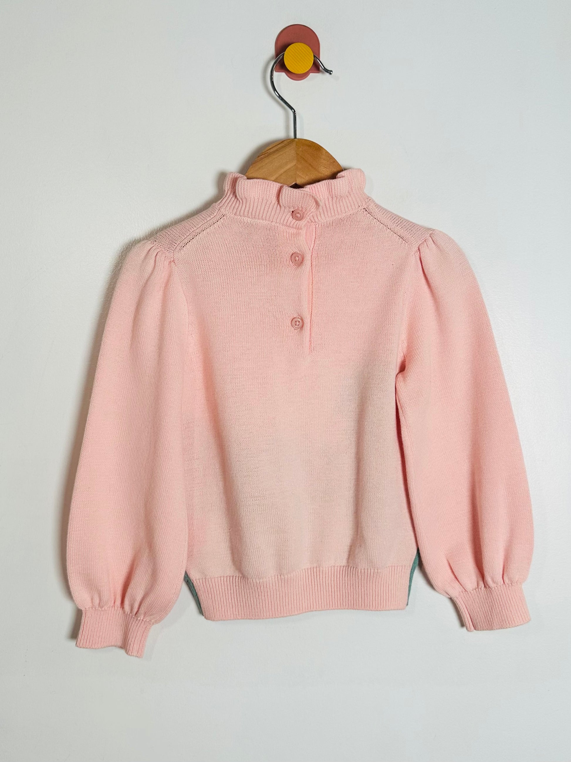 Pink sweater on a hanger against a light gray background