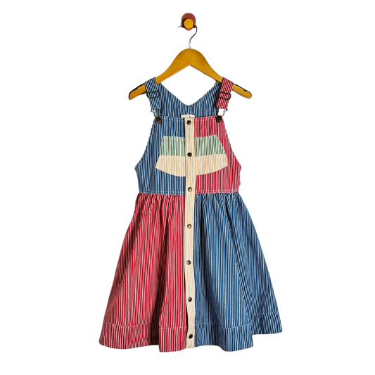 A children's sleeveless dress with a split blue and red striped design, hanging on a wooden hanger against a plain white background.