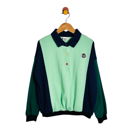 A colorblock long-sleeve polo shirt hanging on a wooden hanger against a white background. The shirt features a mint green body, dark navy blue collar and side panels, and forest green sleeves.