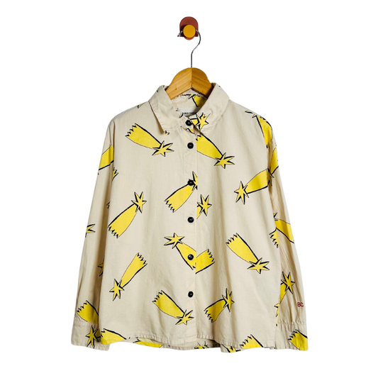 A beige long-sleeve button-up shirt with a yellow and black starburst pattern, hanging on a wooden hanger against a white background.