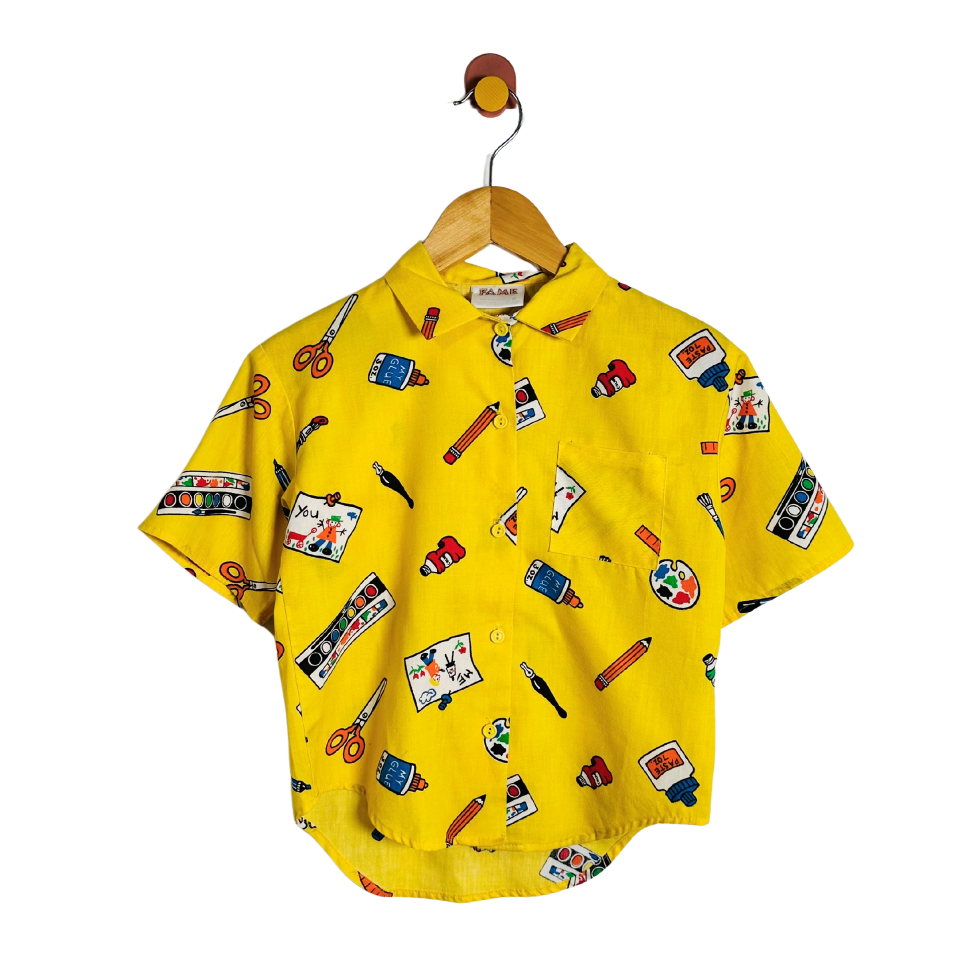 A yellow short-sleeve button-up shirt with an all-over colorful craft-themed print, hanging on a wooden hanger with a brown hook against a plain white background.