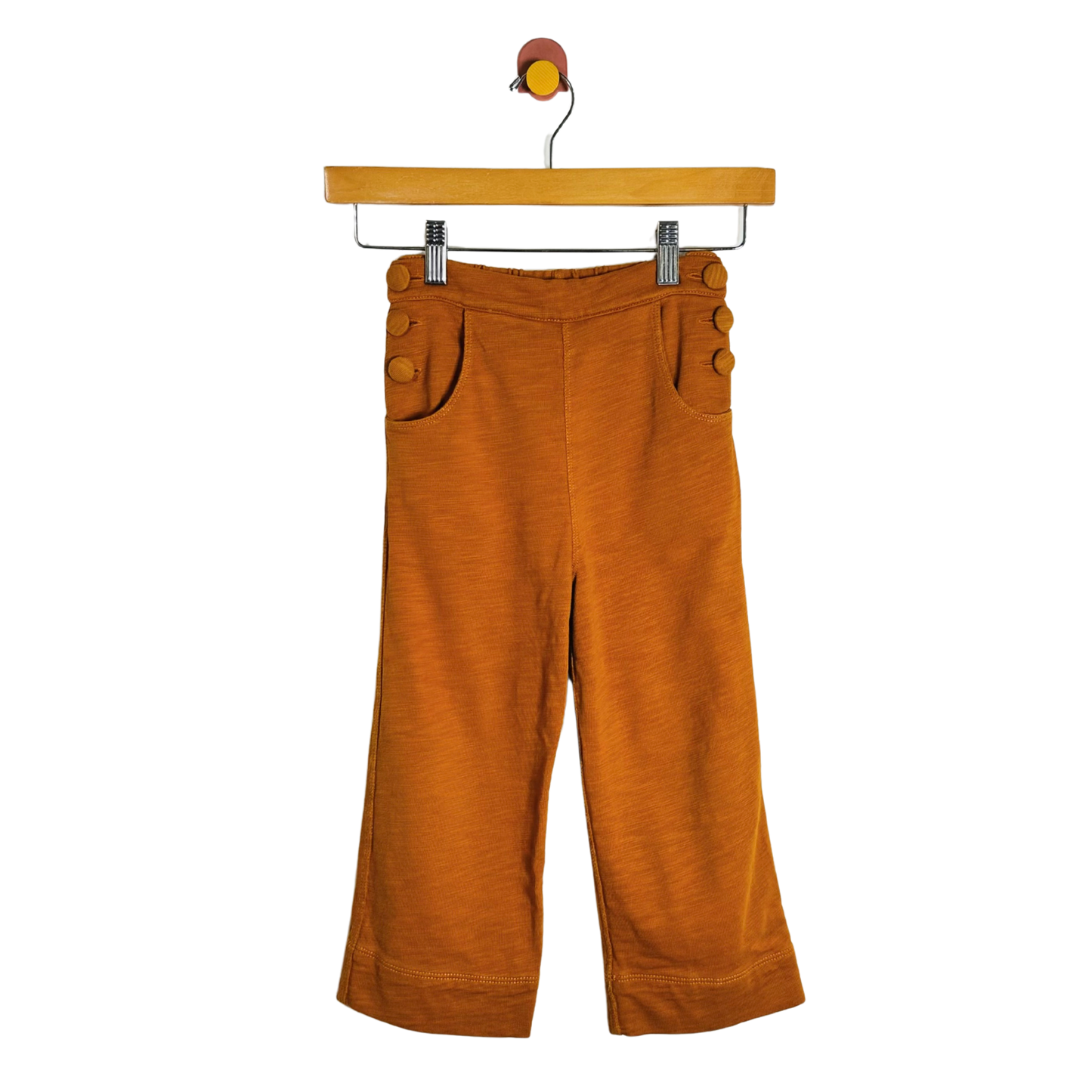 A pair of wide-leg cropped pants in a warm rust-orange corduroy fabric, hanging from a wooden hanger against a plain white background.