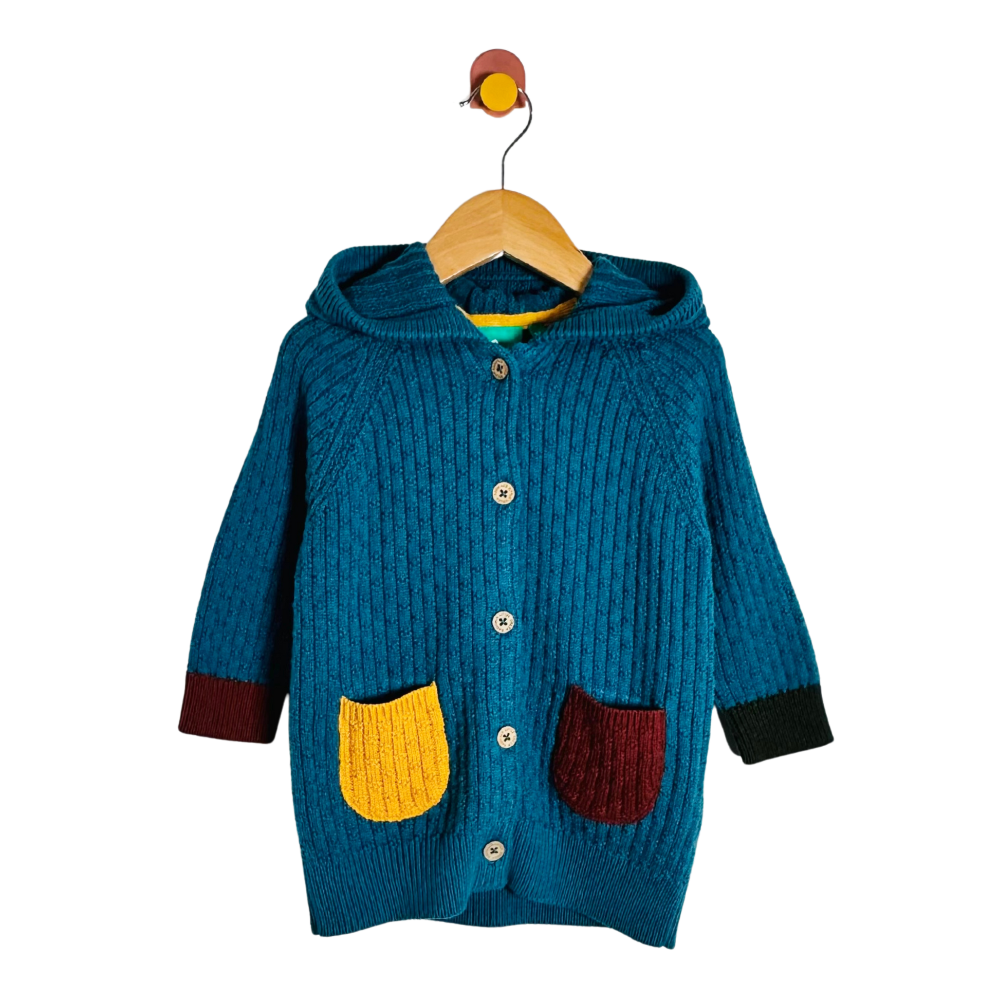 A teal blue ribbed knit hooded cardigan sweater with yellow and burgundy pockets, hanging on a wooden hanger against a white background.