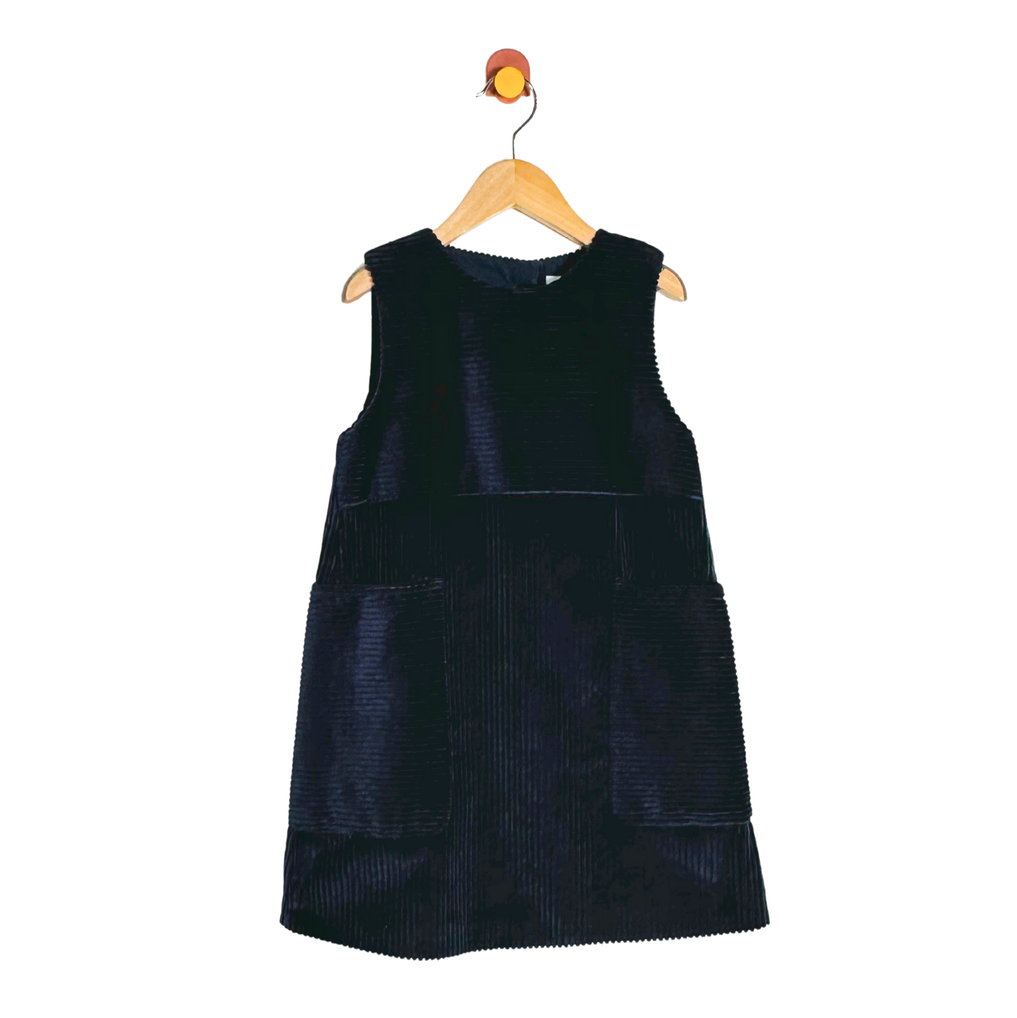 A sleeveless dark navy corduroy dress with front patch pockets, hanging on a wooden hanger against a plain white background.