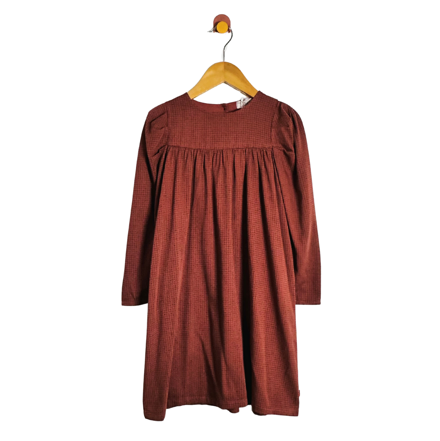 A rust-colored long-sleeve dress with a textured pattern, hanging on a wooden hanger against a plain white background.