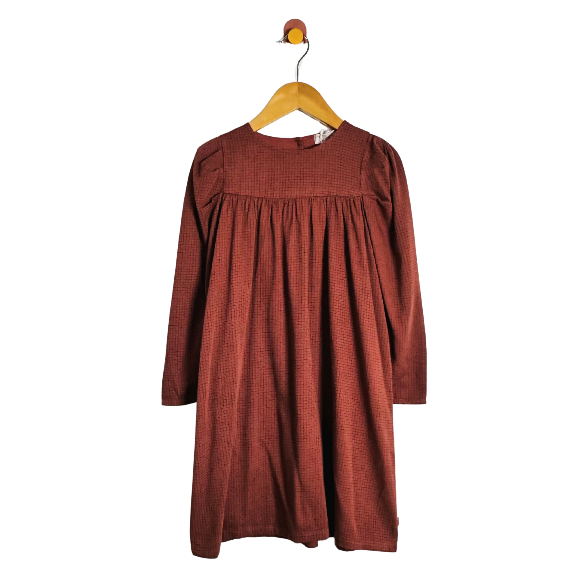 A rust-colored long-sleeve dress with a textured pattern, hanging on a wooden hanger against a plain white background.