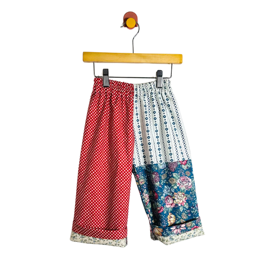 Colorful patchwork pants on a hanger against a white background