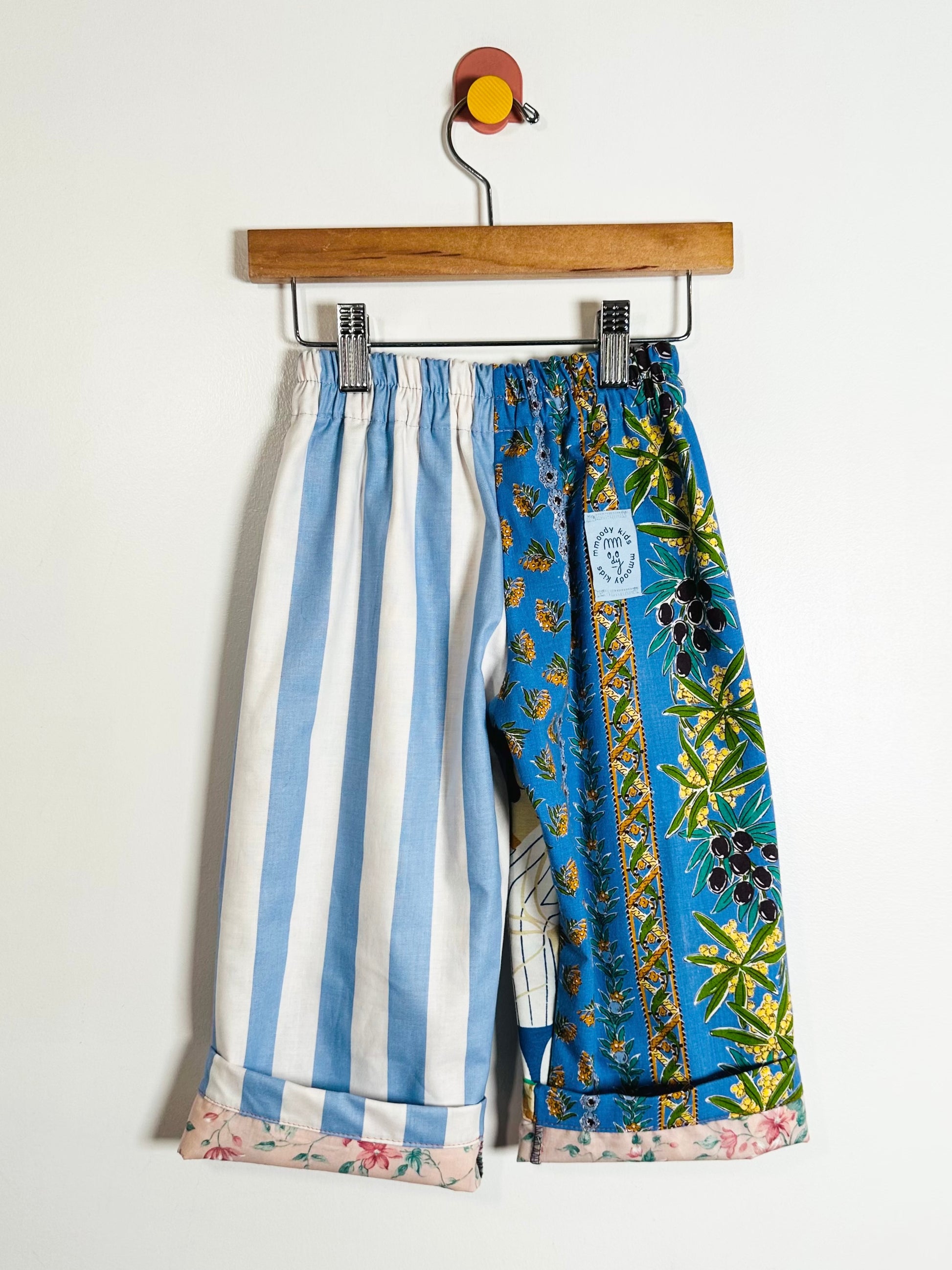 Colorful patterned pants on a hanger against a white background