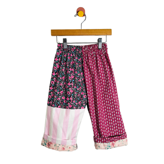 Colorful patterned pants on a hanger against a white background