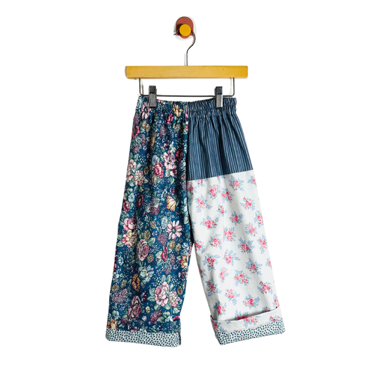 Floral-patterned pants on a hanger against a white background