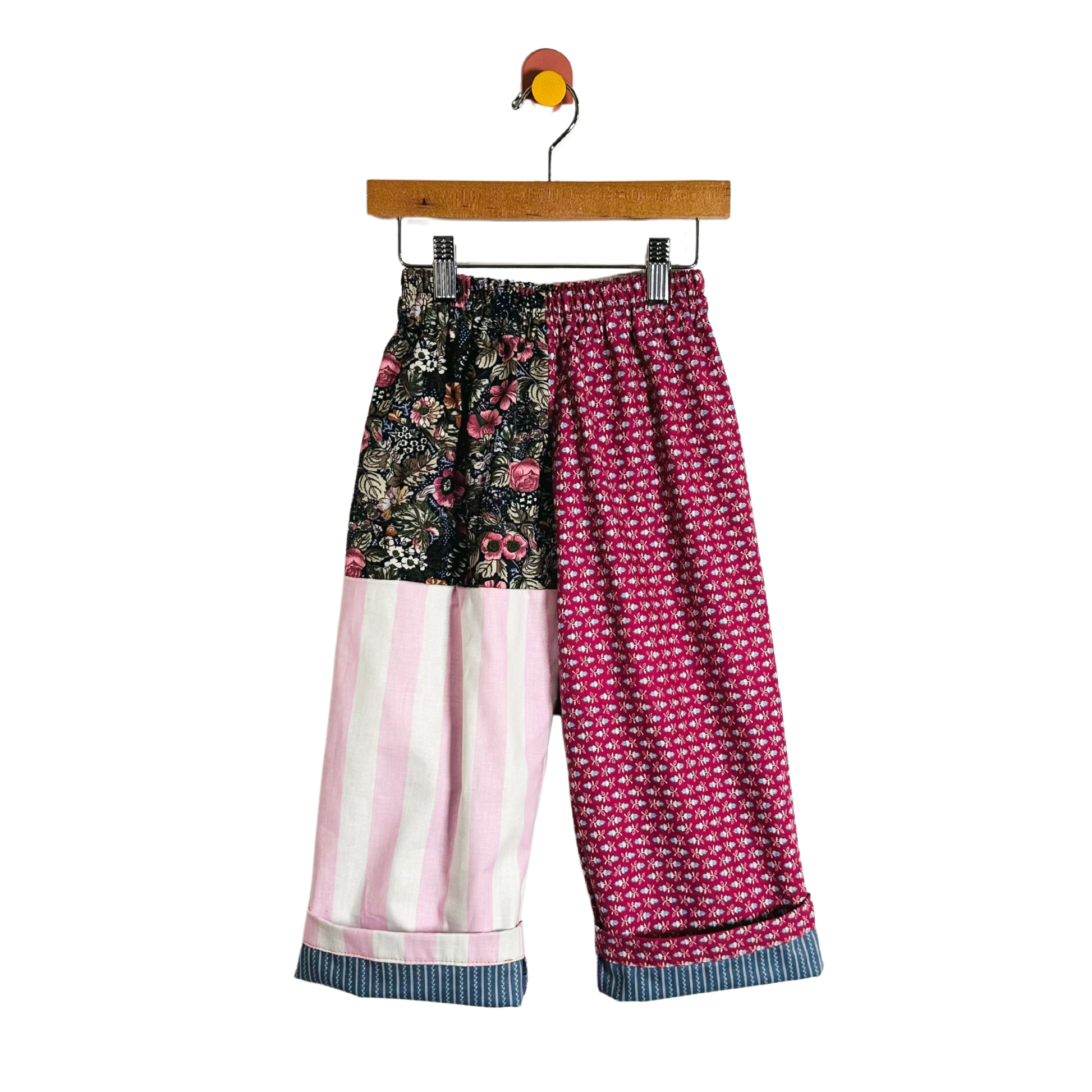 Colorful patterned pants on a hanger against a white background