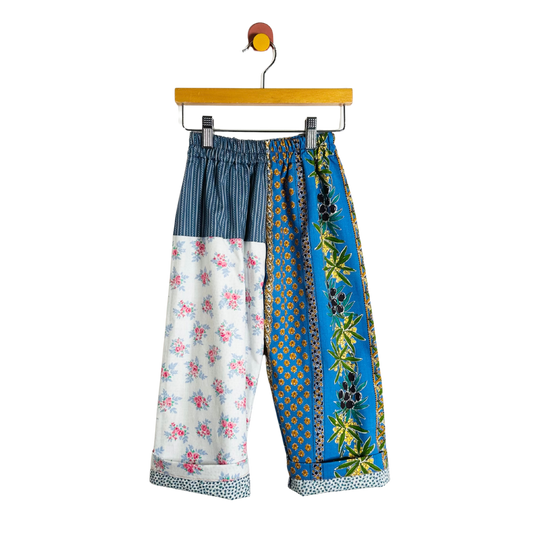 Colorful patchwork pants on a hanger against a white background