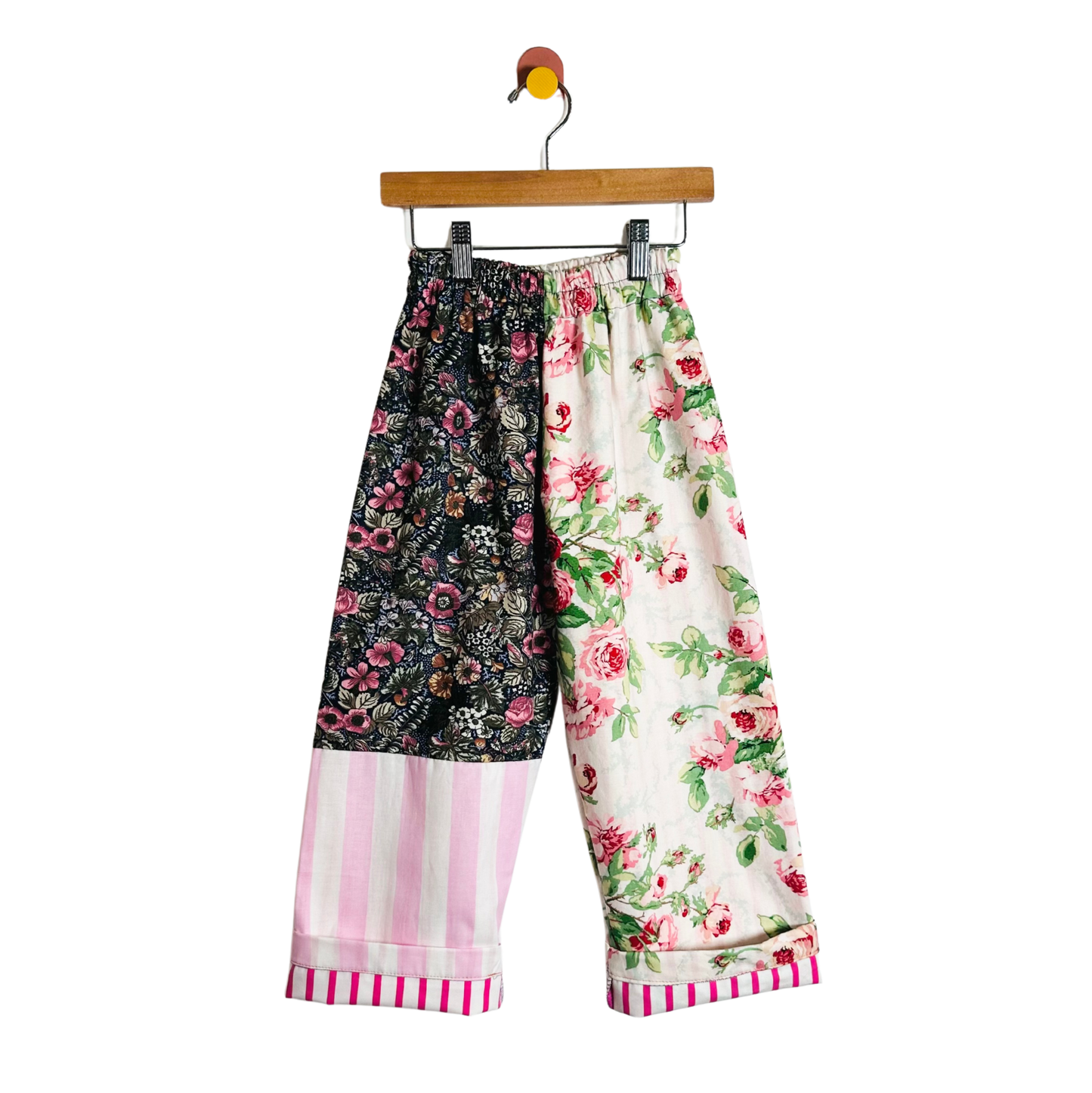 Colorful patchwork pants on a hanger against a white background