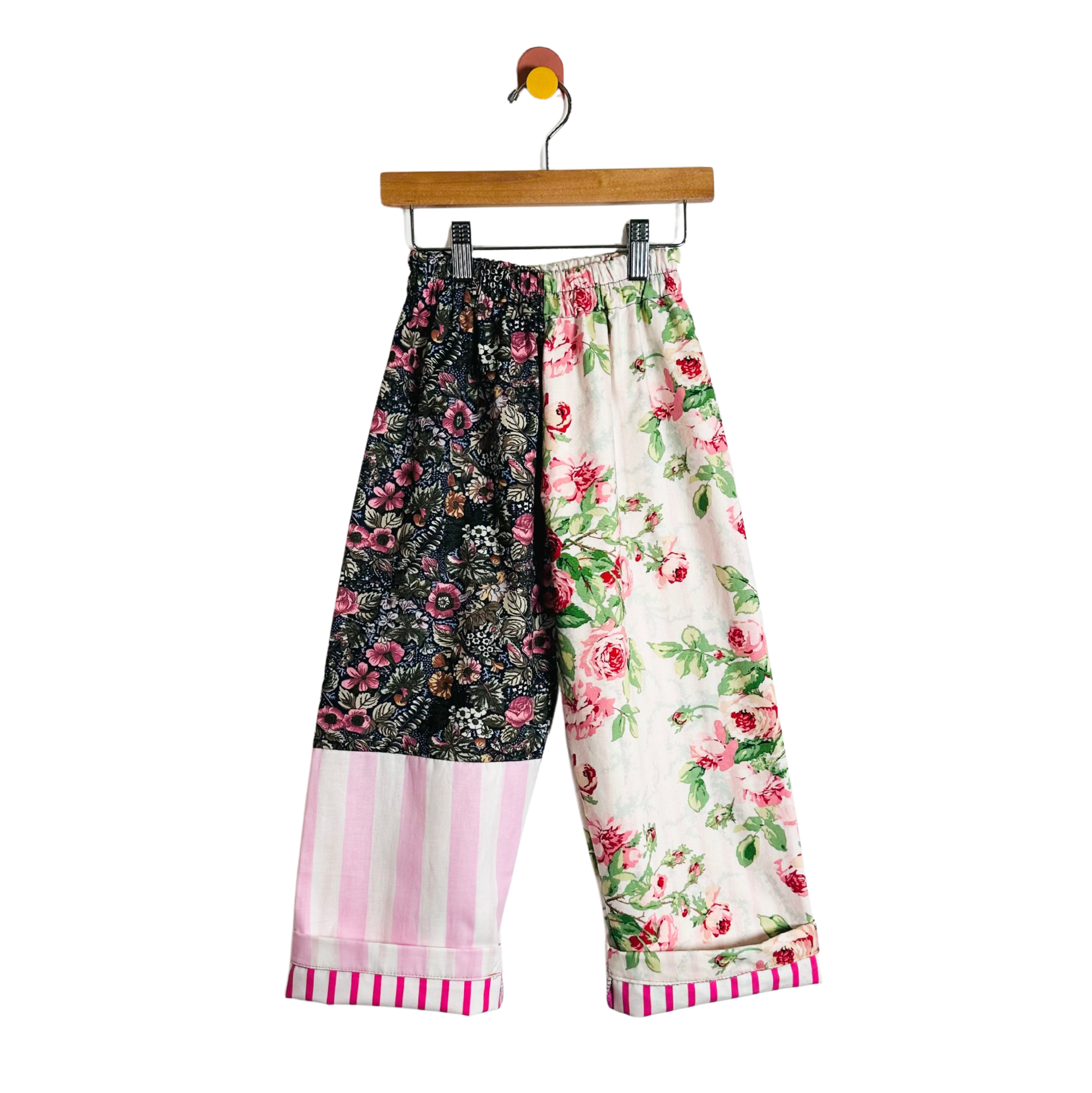 Colorful patchwork pants on a hanger against a white background