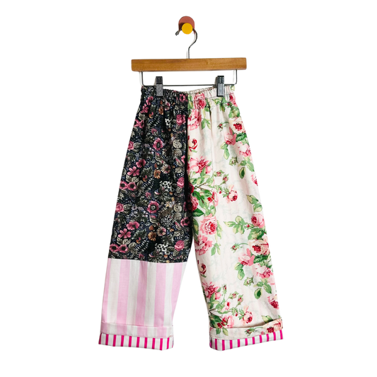 Colorful patchwork pants on a hanger against a white background